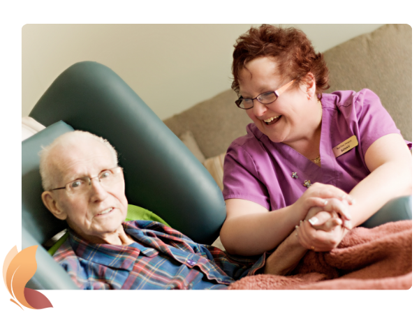 Smiling Red Deer Hospice staff member holding hands of older gentleman in care.