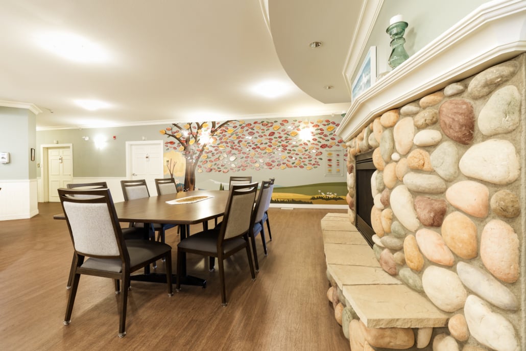 Large dining table with chairs next to stone fireplace.